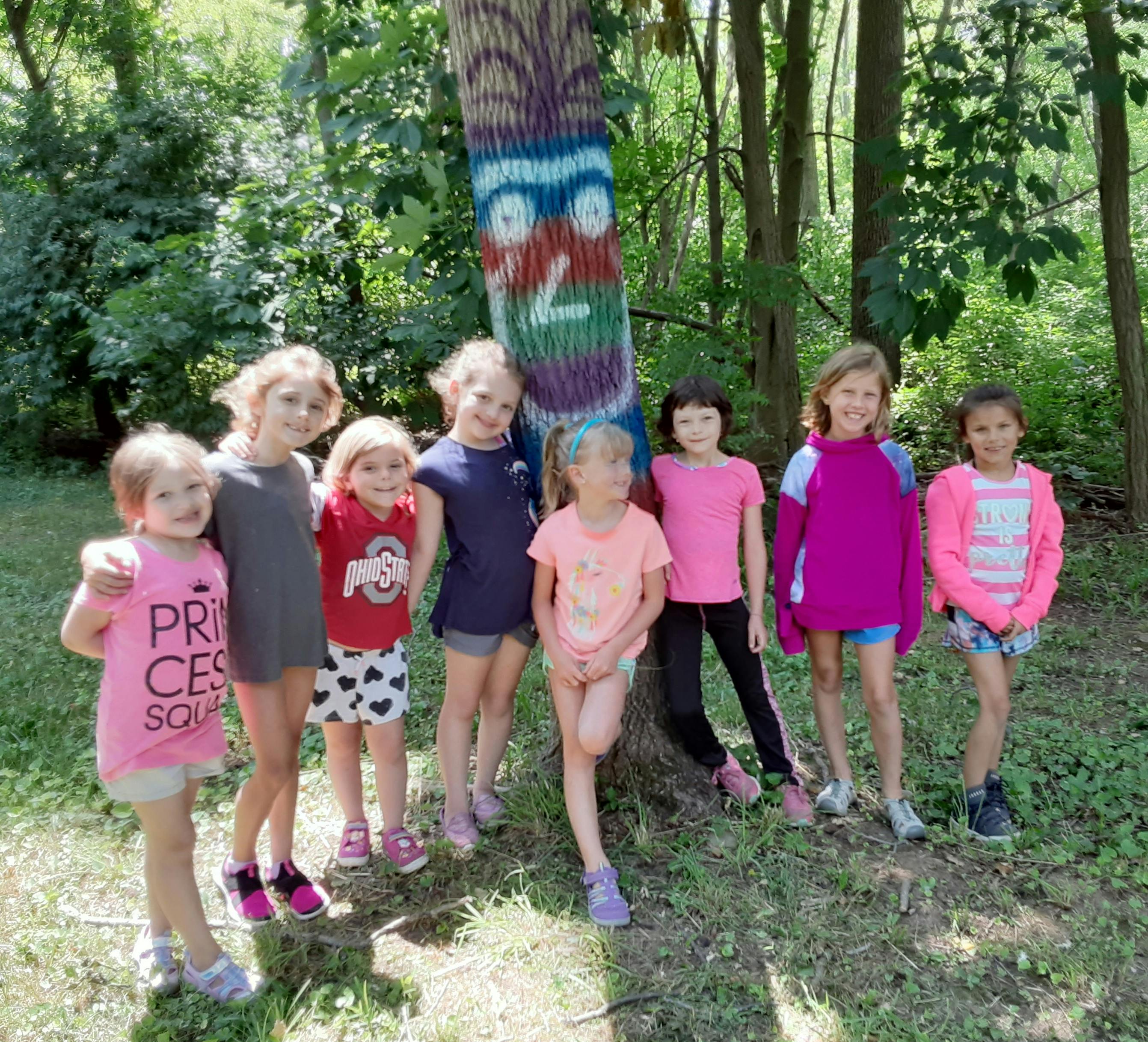 Group of children standing in front of a tree with painted faces