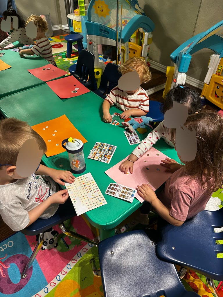 children making crafts with stickers at a green table