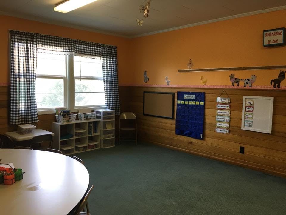 Empty classroom with windows, tables, and wall decorations