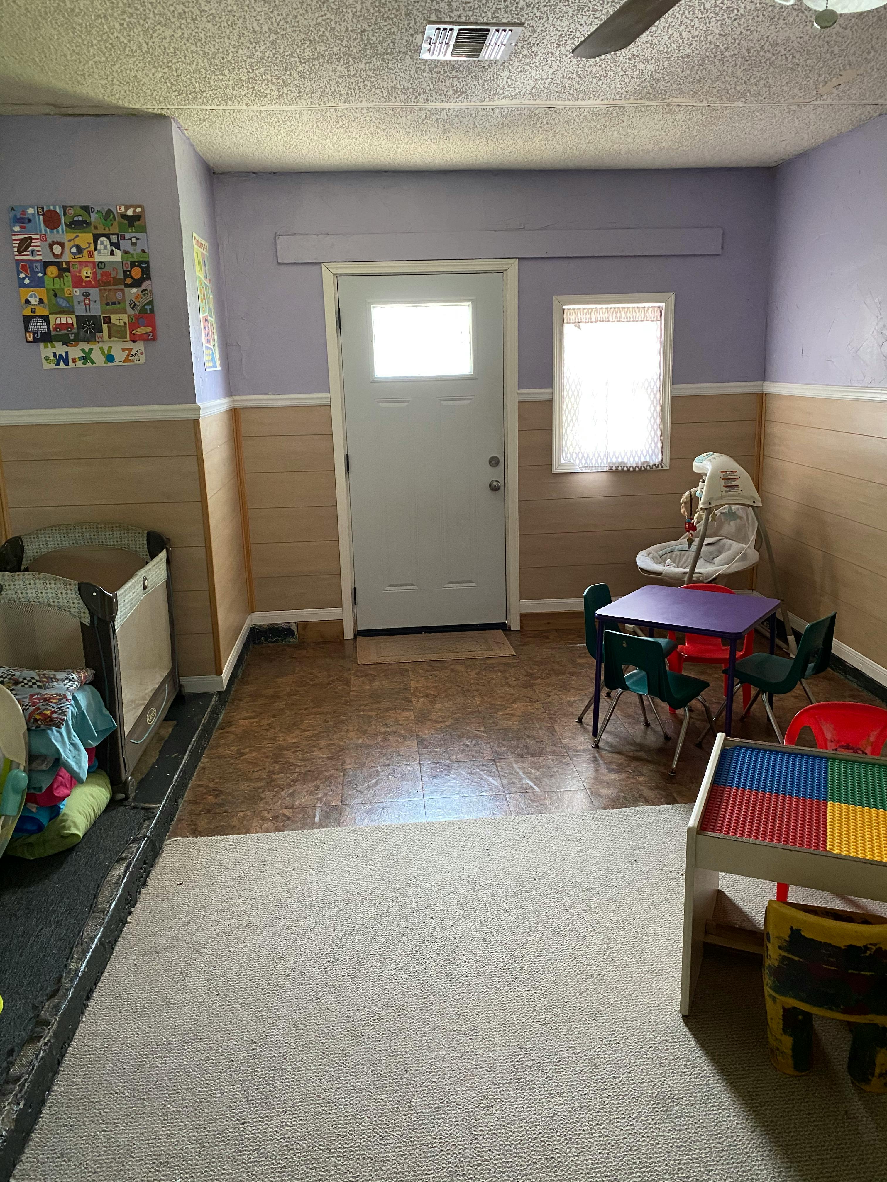Room with a crib, small table and chairs, and a play table