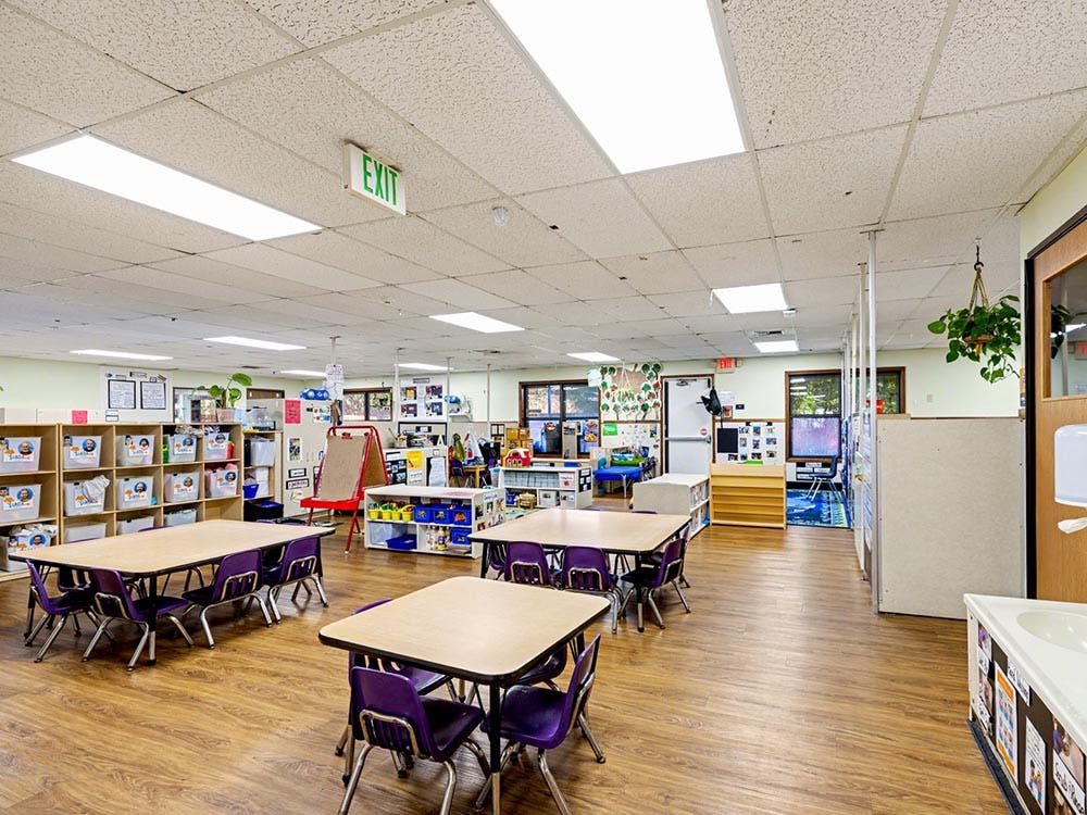 Empty classroom with tables, chairs, and learning materials
