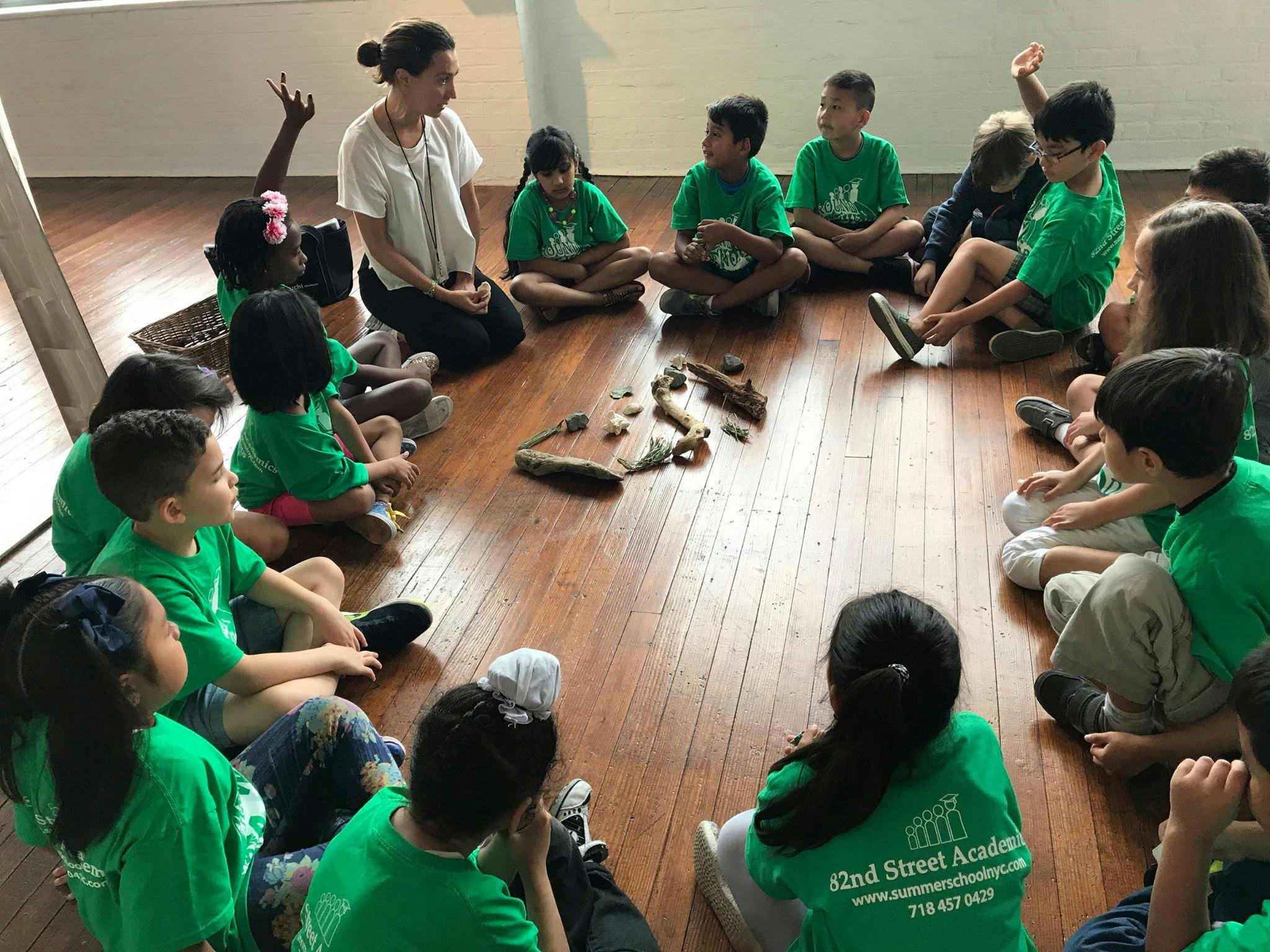 Adult and children sitting in a circle on a wooden floor