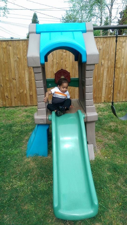 Child sitting at the top of a playground slide