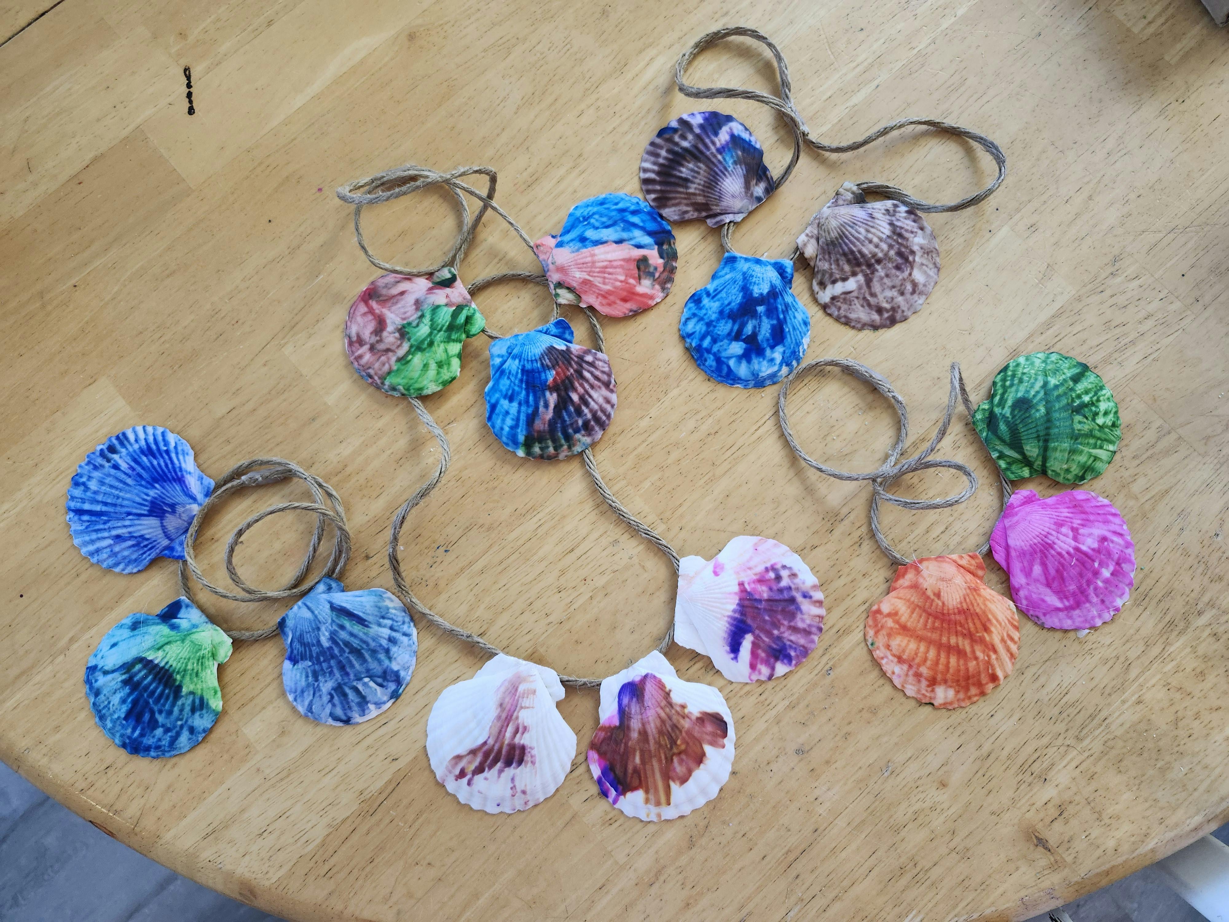 Colorful hand-painted seashells strung together on twine on a wooden table