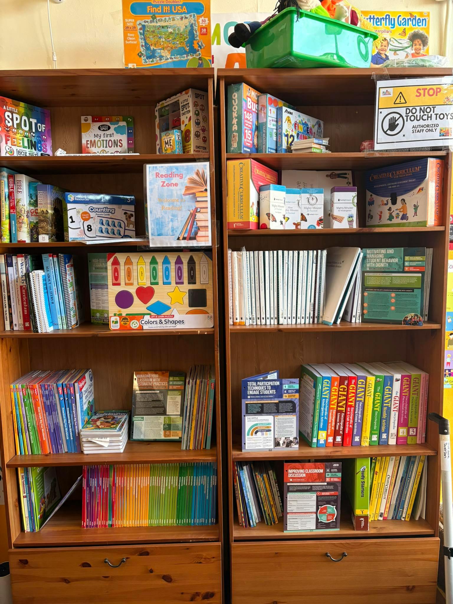 Two wooden bookshelves filled with books and educational materials