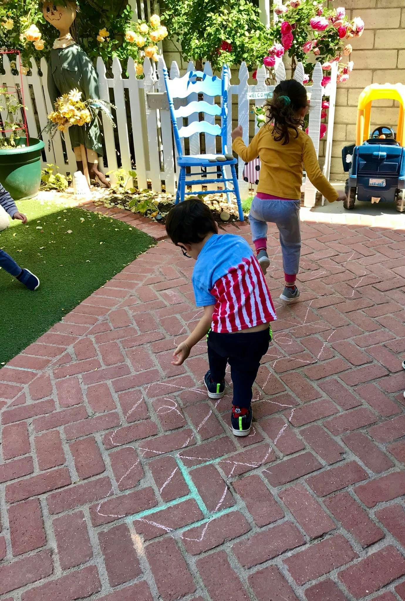 Child drawing with chalk on a brick patio