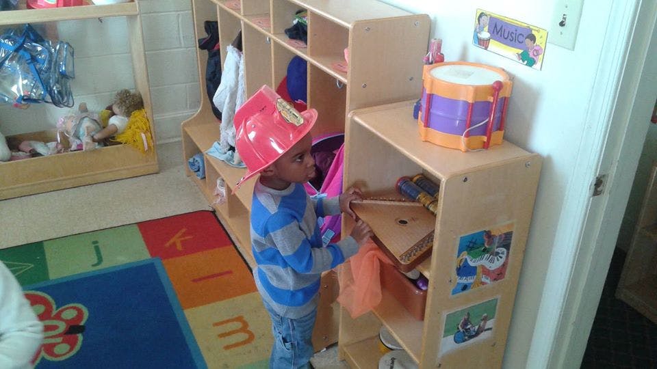 Child in a red hat looking into a shelf