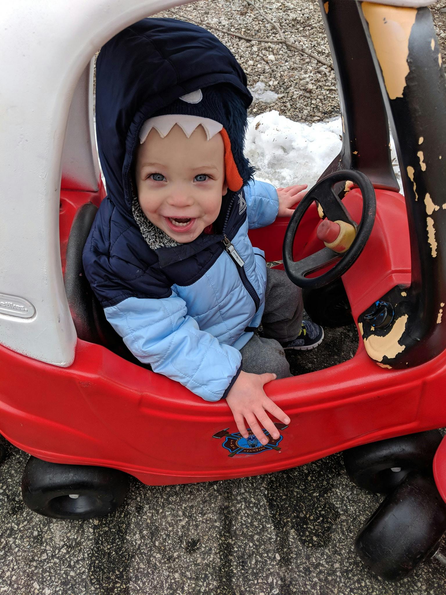 Child in a red toy car