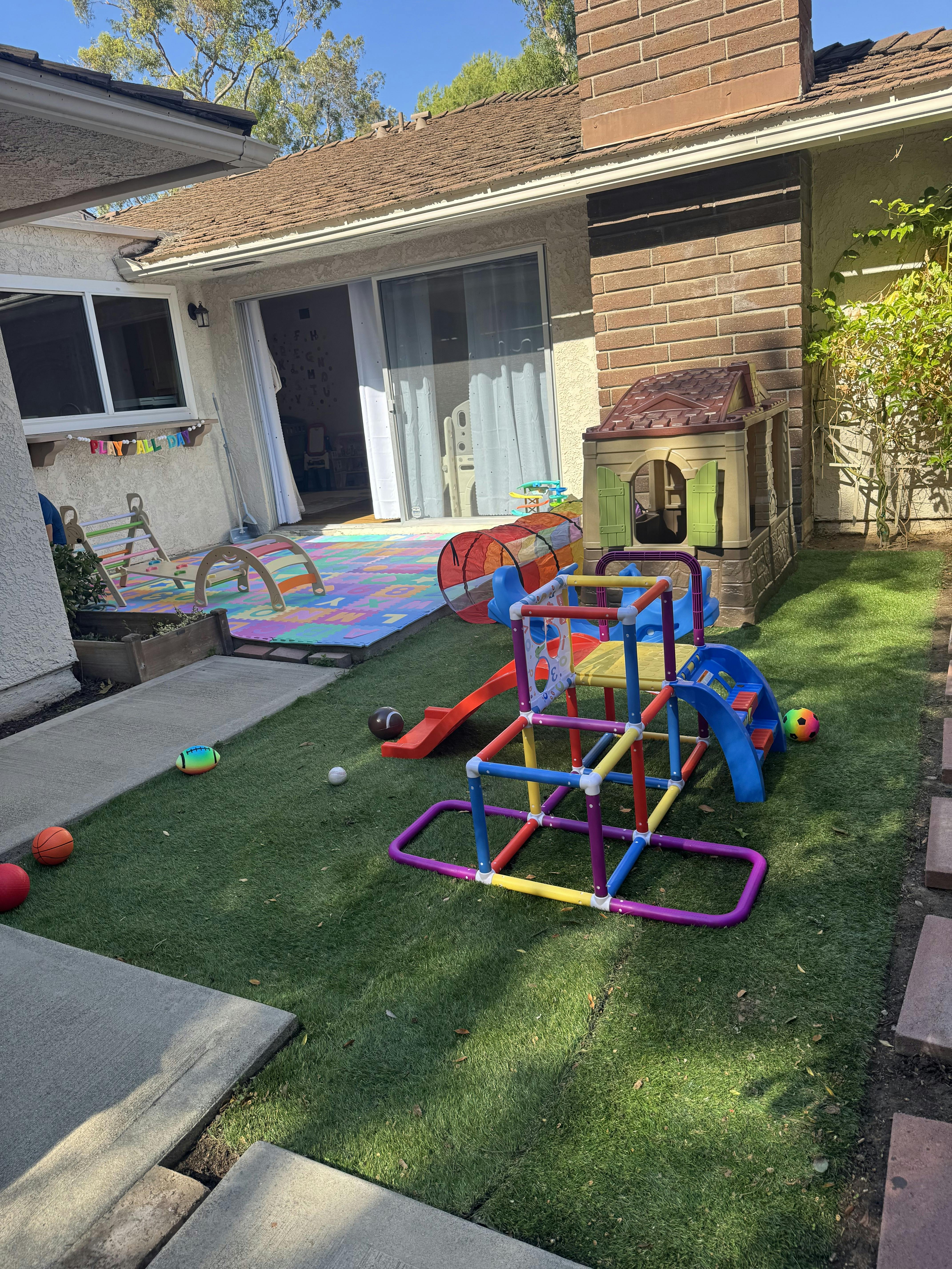 Backyard with play equipment including a slide, tunnel, and playhouse