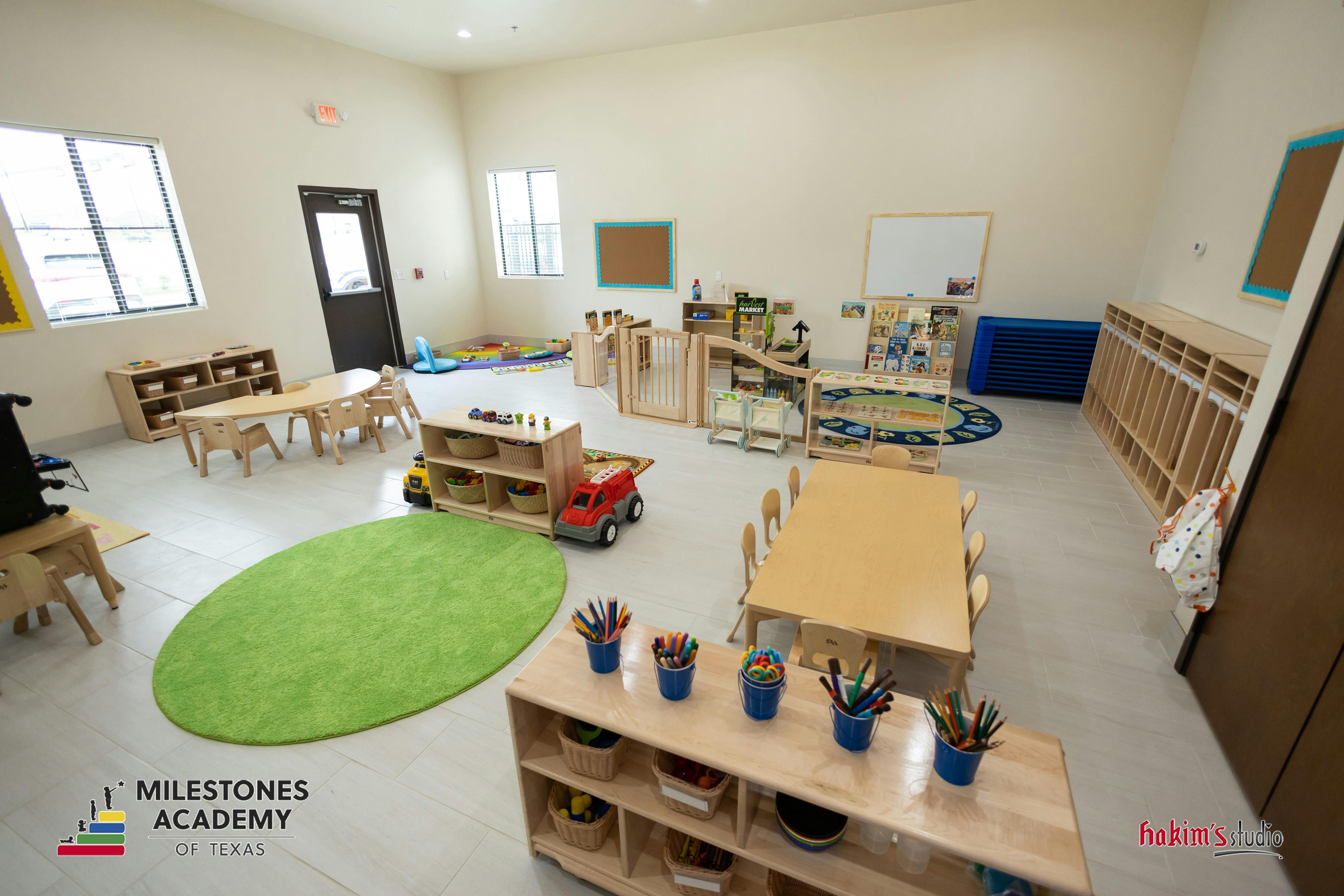 Classroom with small wooden tables and chairs, toys, and shelving units