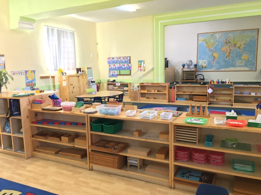 Classroom with wooden shelves filled with learning materials and a world map