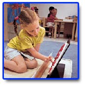 Child kneeling and pointing at a book in a classroom