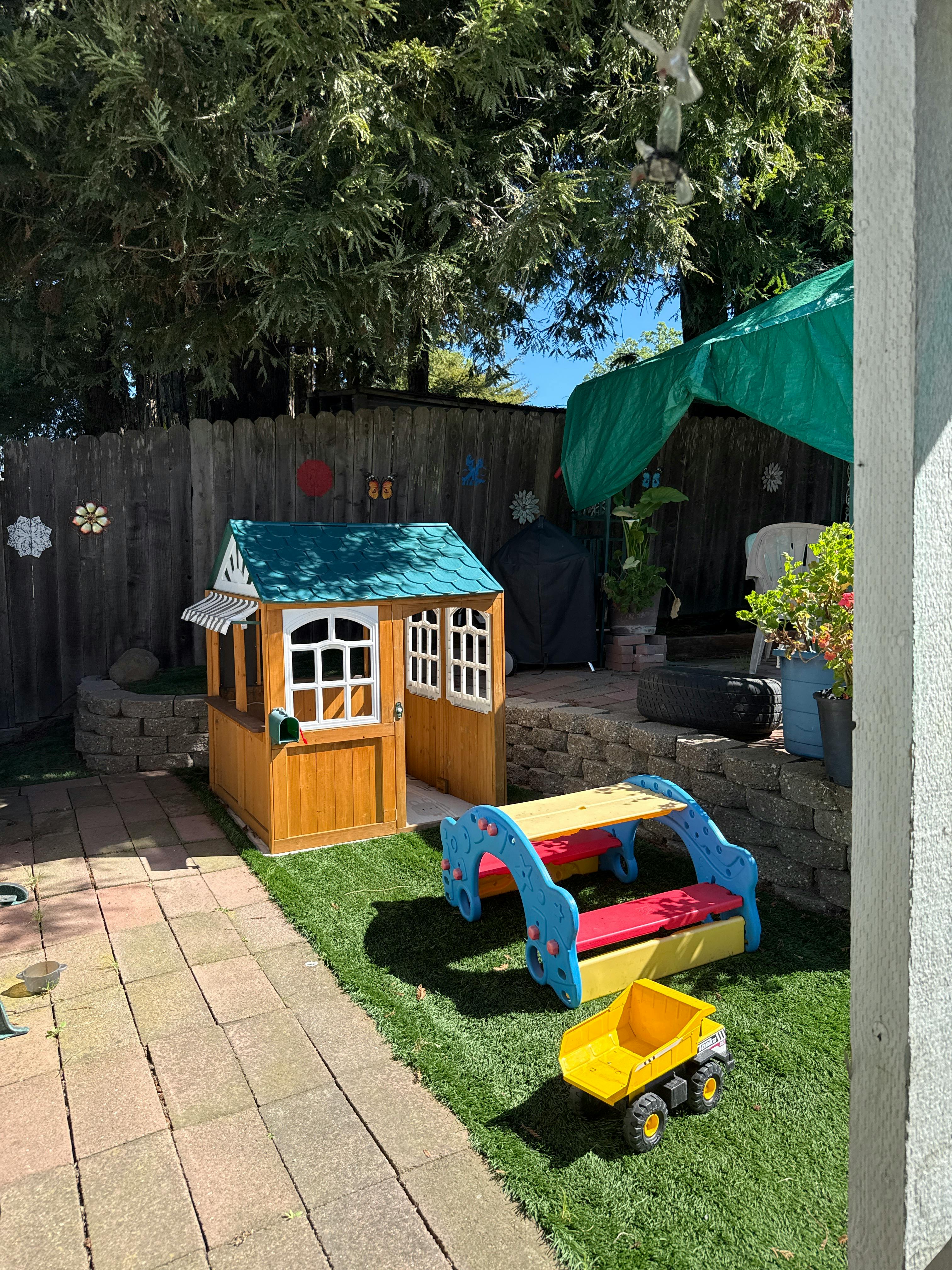 Wooden playhouse and colorful slide in a grassy backyard
