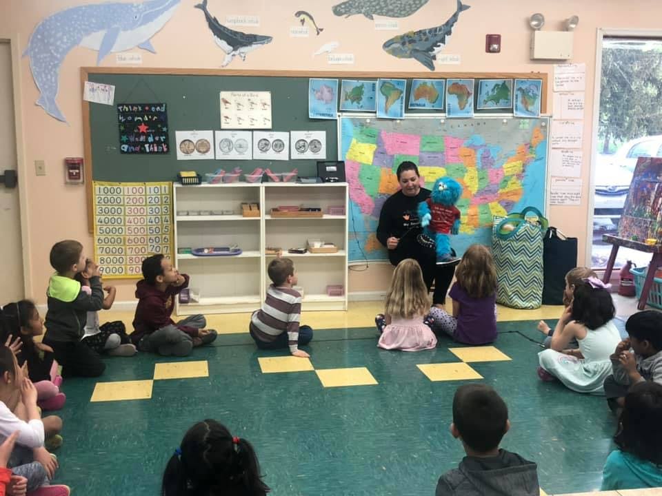 Person with puppet teaching children in a classroom