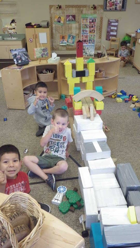 Three children playing with blocks on the floor in a classroom