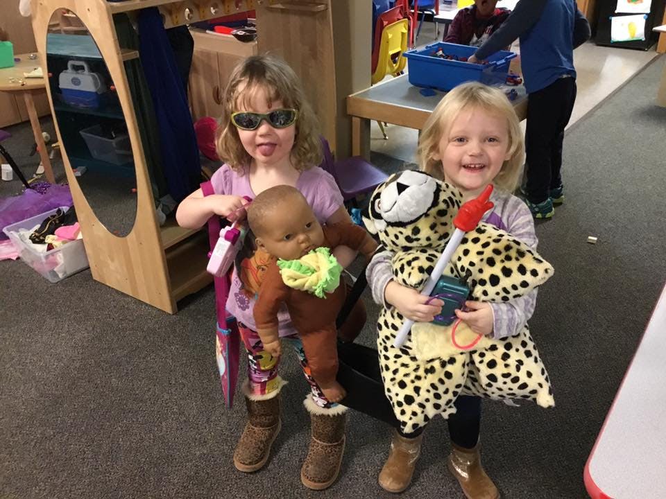 Two children holding a doll and a stuffed animal