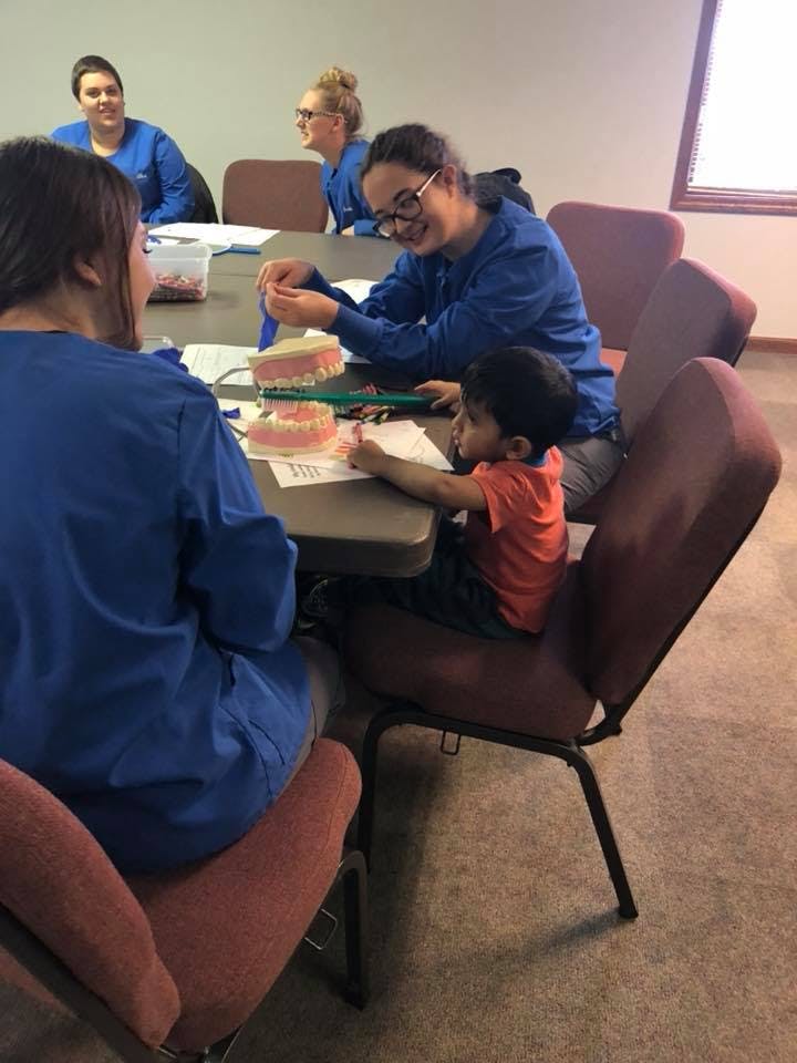 People and a child at a table with dental models