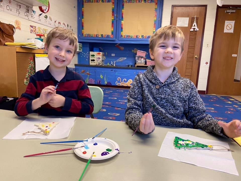 Two children painting at a table in a classroom