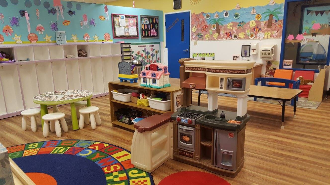 Playroom with toy kitchen, small table and chairs, and colorful rug