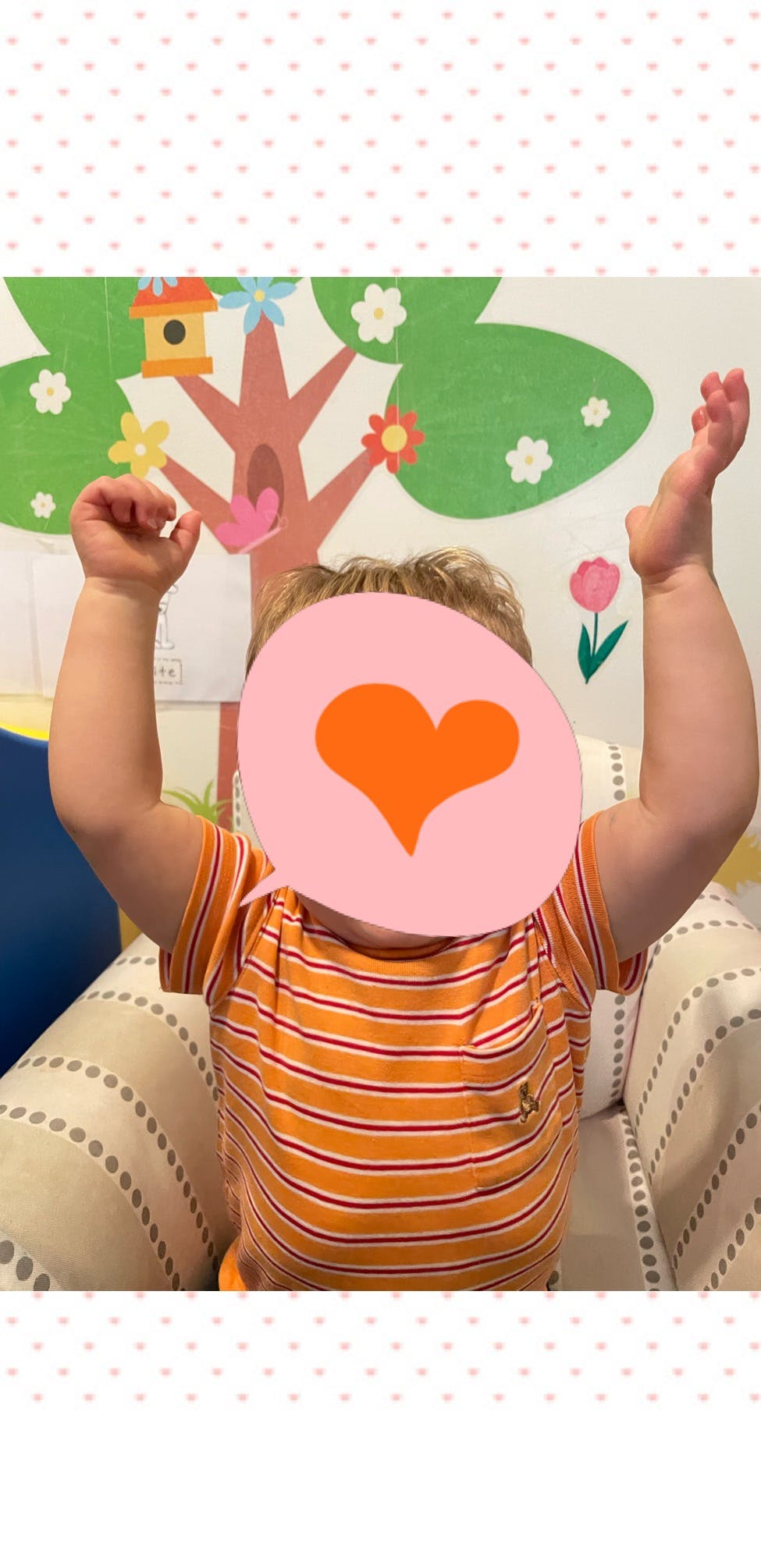 Child with arms raised, sitting in a chair