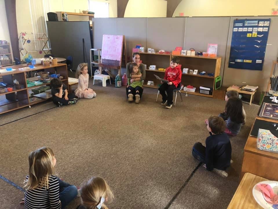 Adult and children sitting on the floor in a classroom