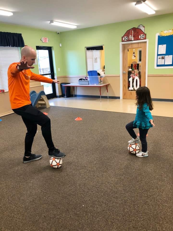 Adult and child playing with soccer balls indoors