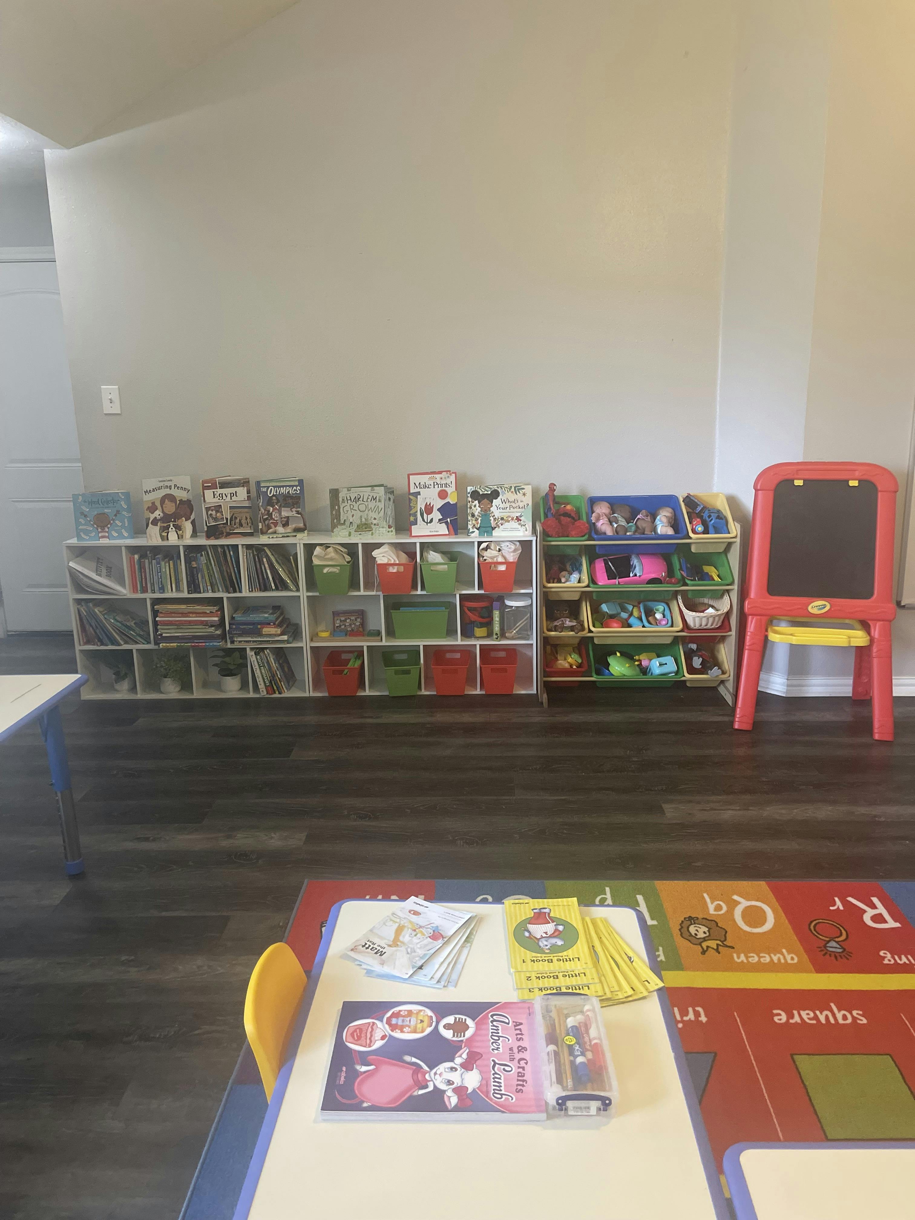 Classroom with bookshelves, toy organizer, easel, and table with learning materials