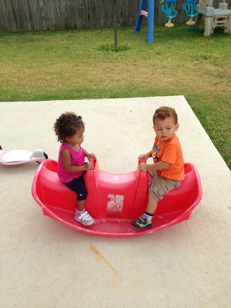 Two children on a red seesaw toy