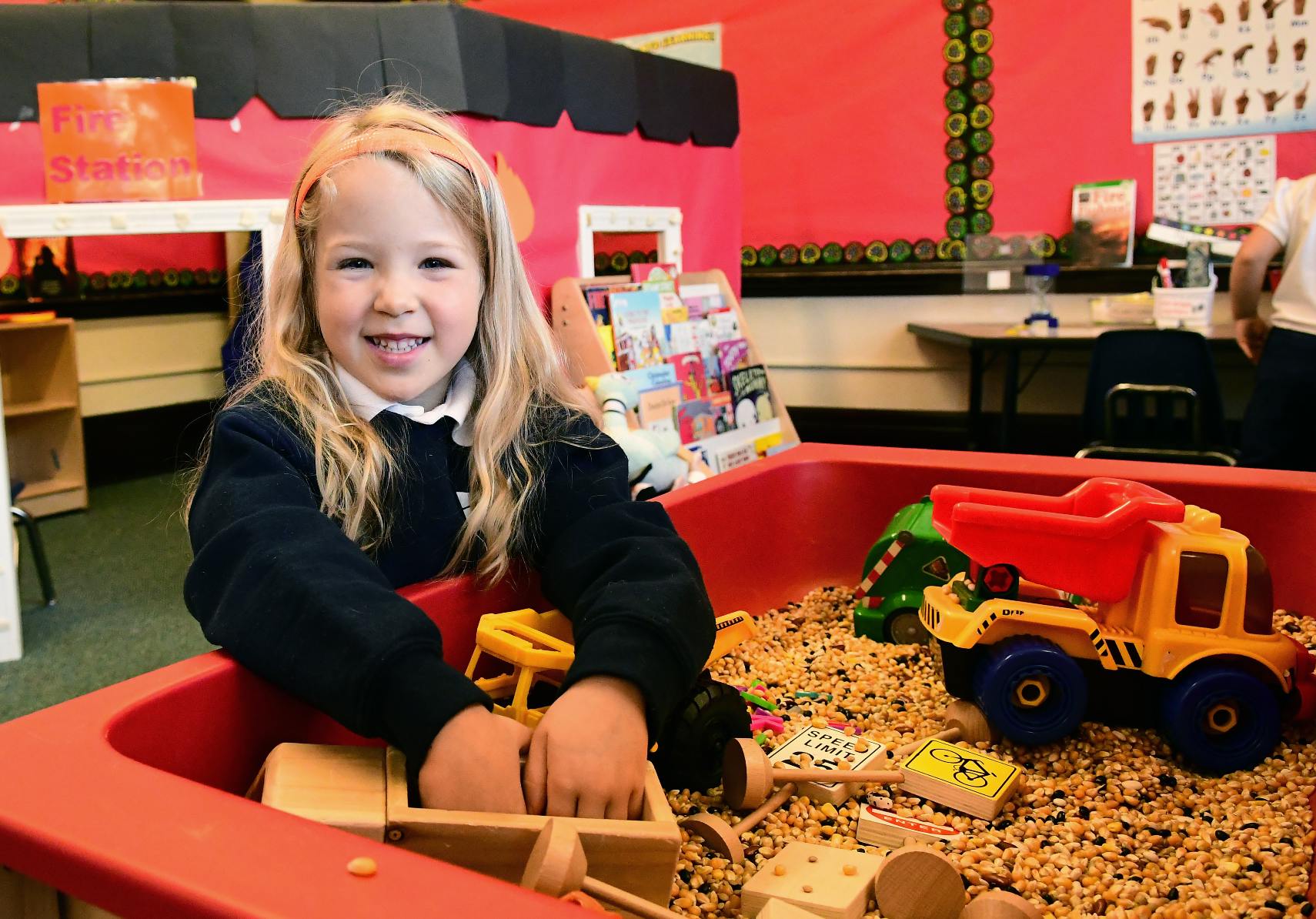 Child playing in a sensory bin with toys in a classroom