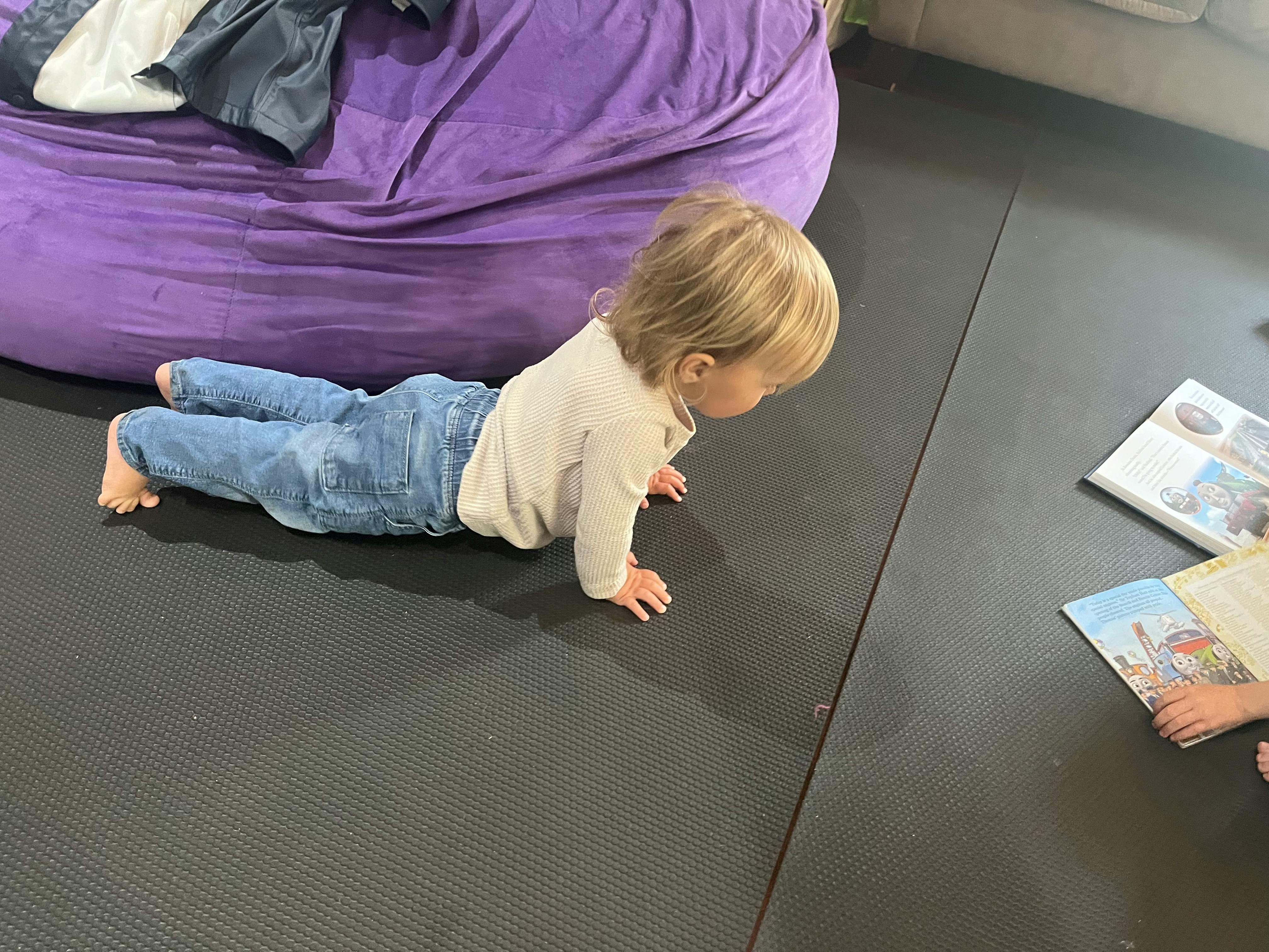 Child on hands and knees looking at open books on the floor