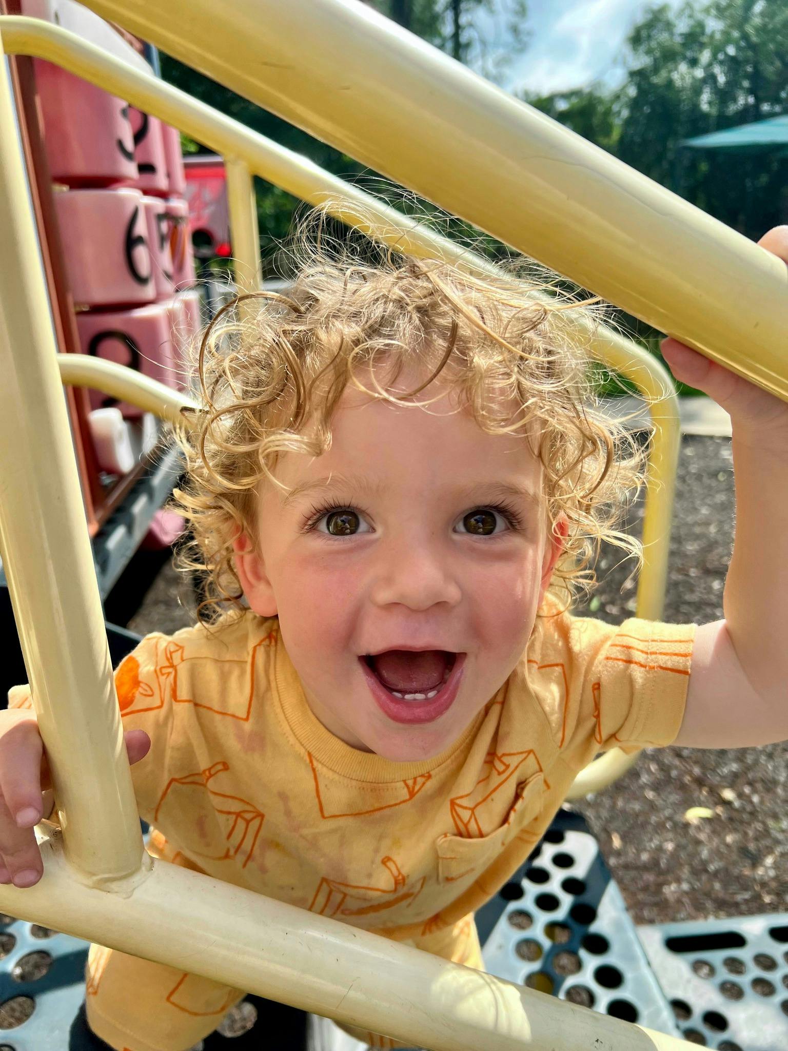 Child smiling while looking up through playground equipment