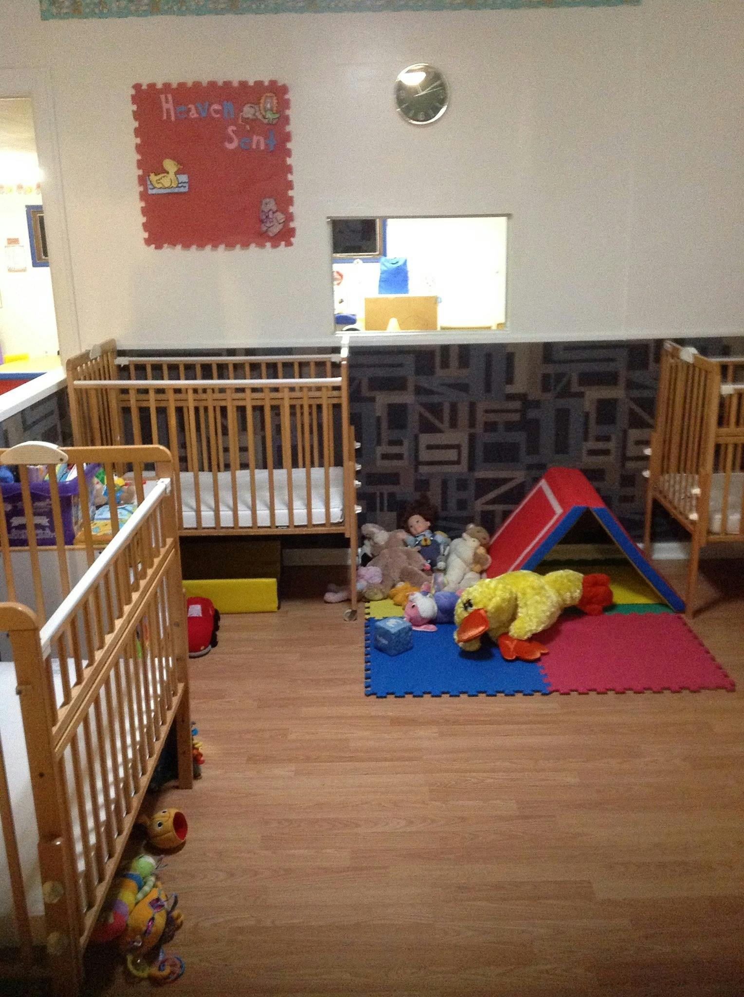 Nursery room with multiple cribs, play mat, and toys