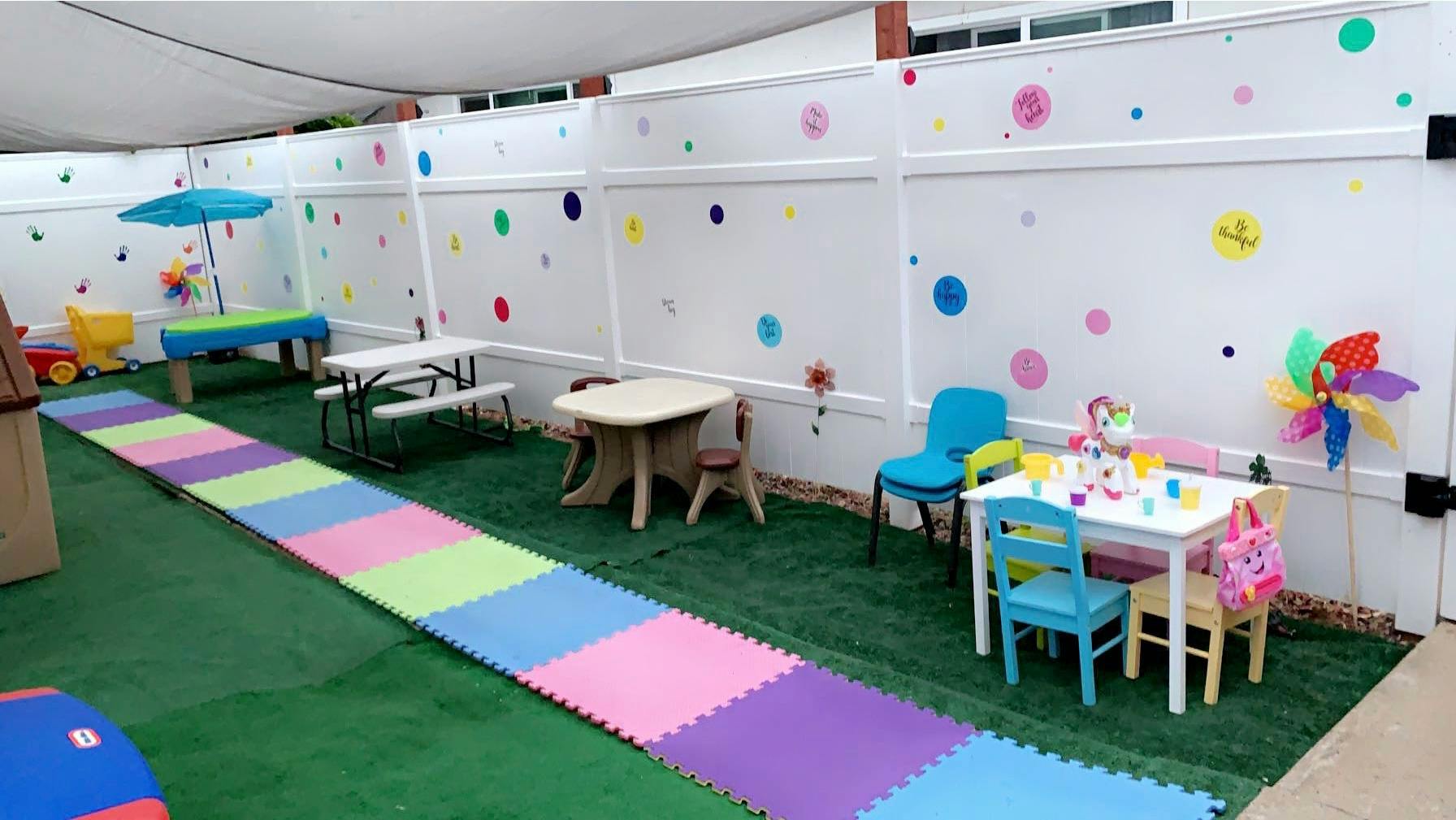 Play area with artificial grass, colorful mats, and small tables and chairs