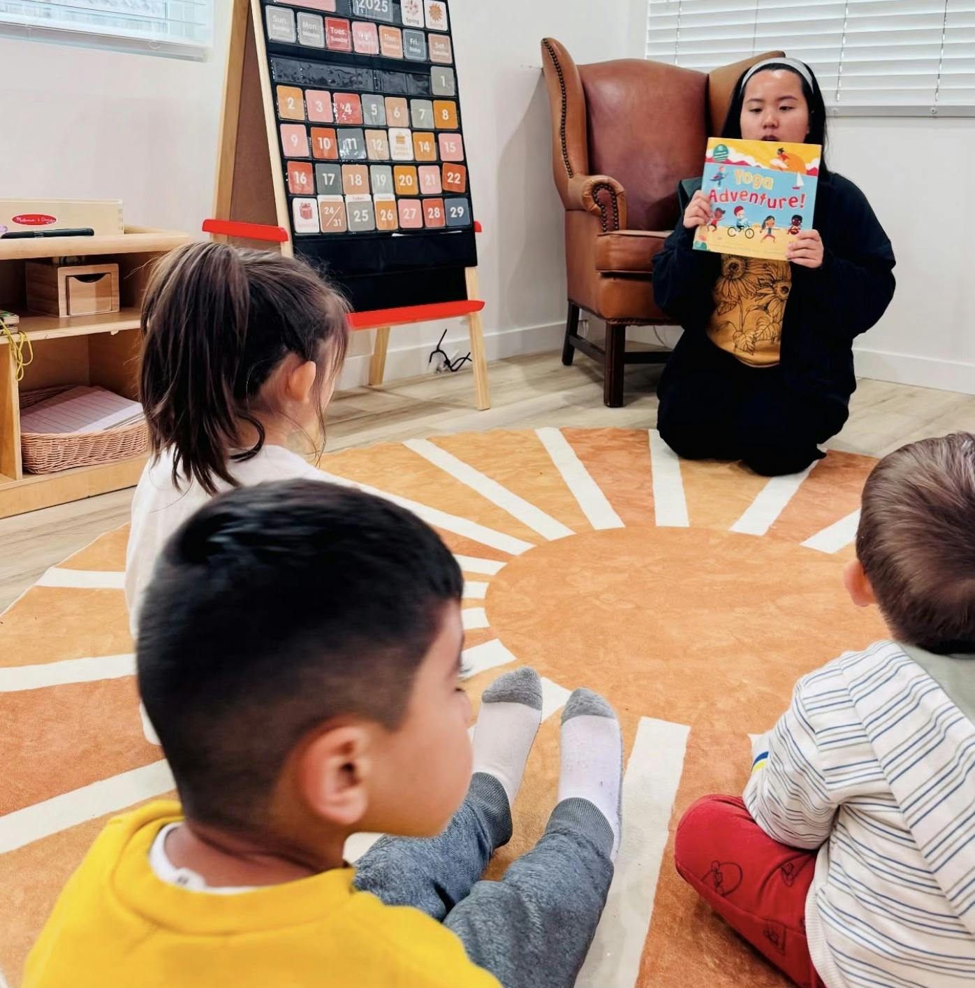 Person reading a book to children sitting on a rug