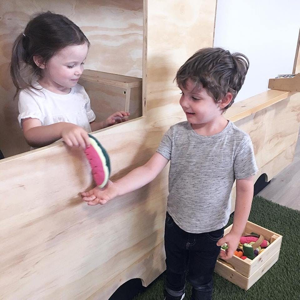 Child handing a toy watermelon to another child