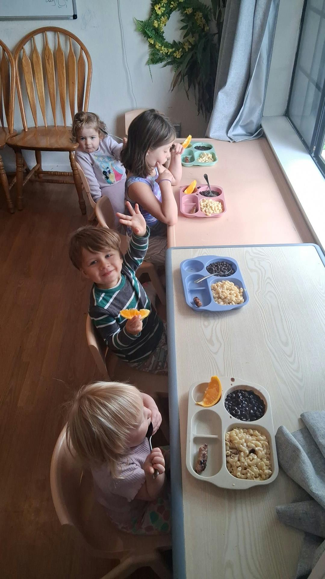 Several children sitting at a table with plates of food