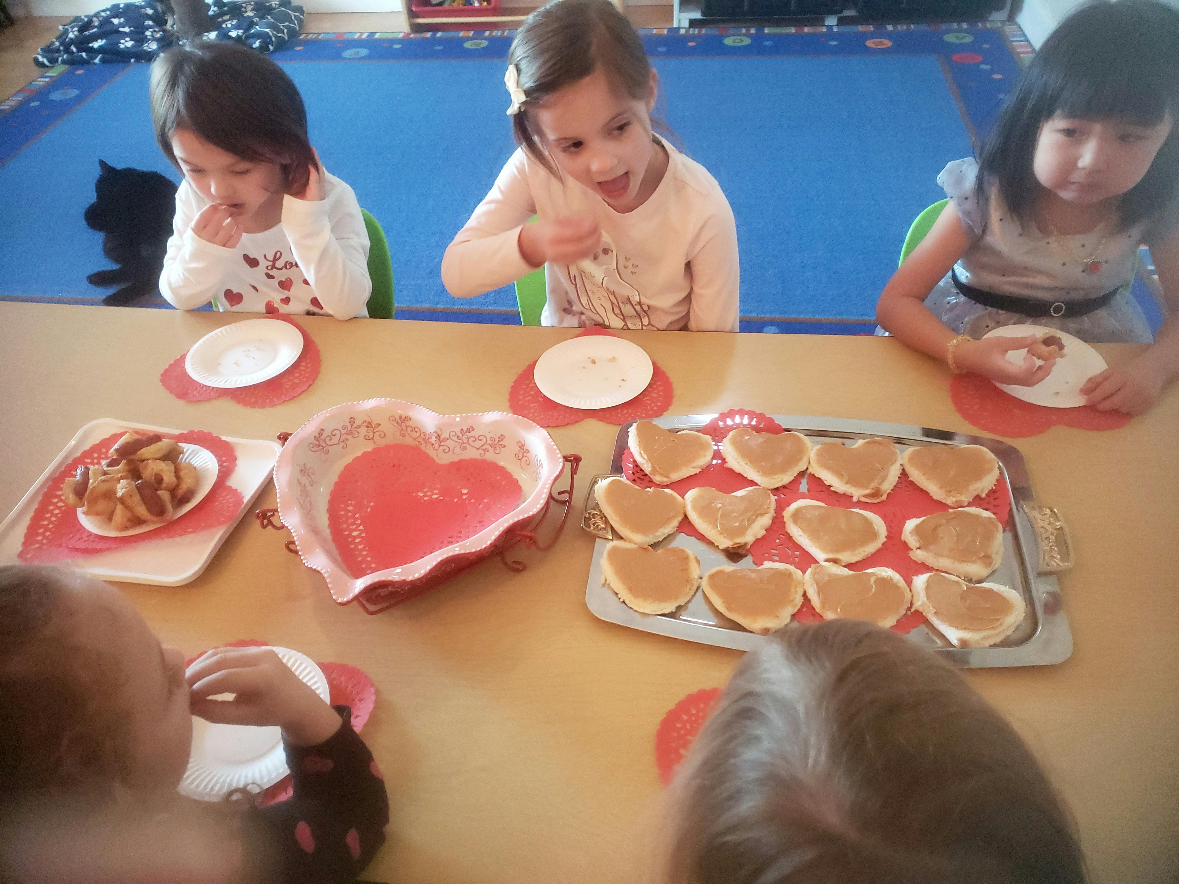 Children at a table with heart-shaped pancakes and a heart-shaped bowl