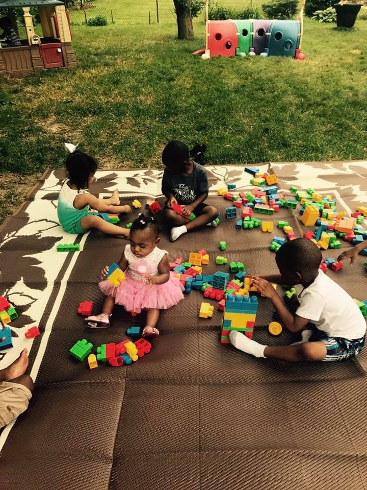 Children playing with colorful building blocks on a mat outdoors