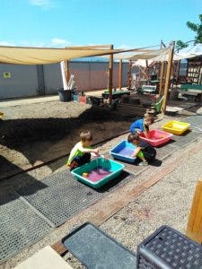 Children playing with water in bins outdoors