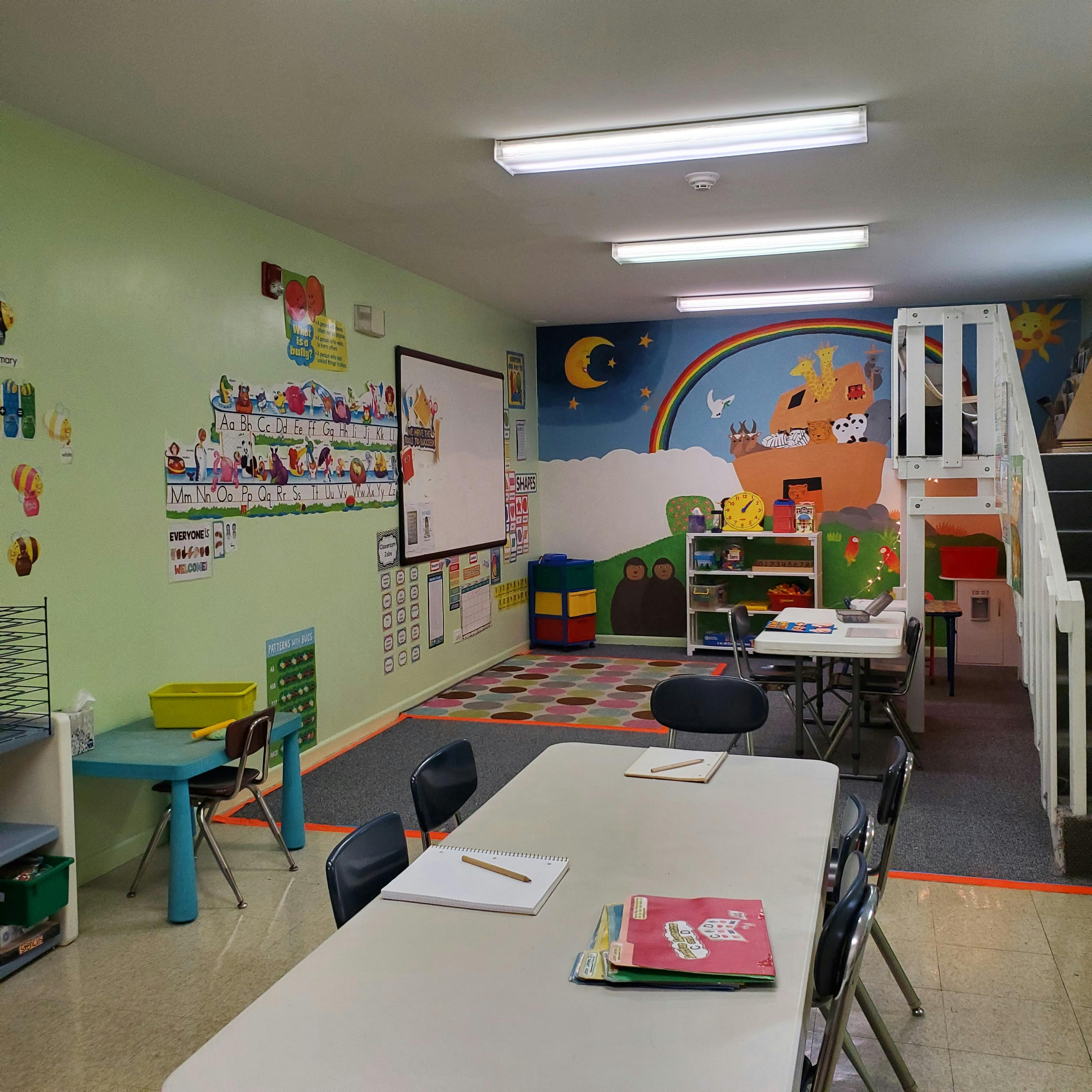 Classroom with tables, chairs, and a colorful mural on the wall