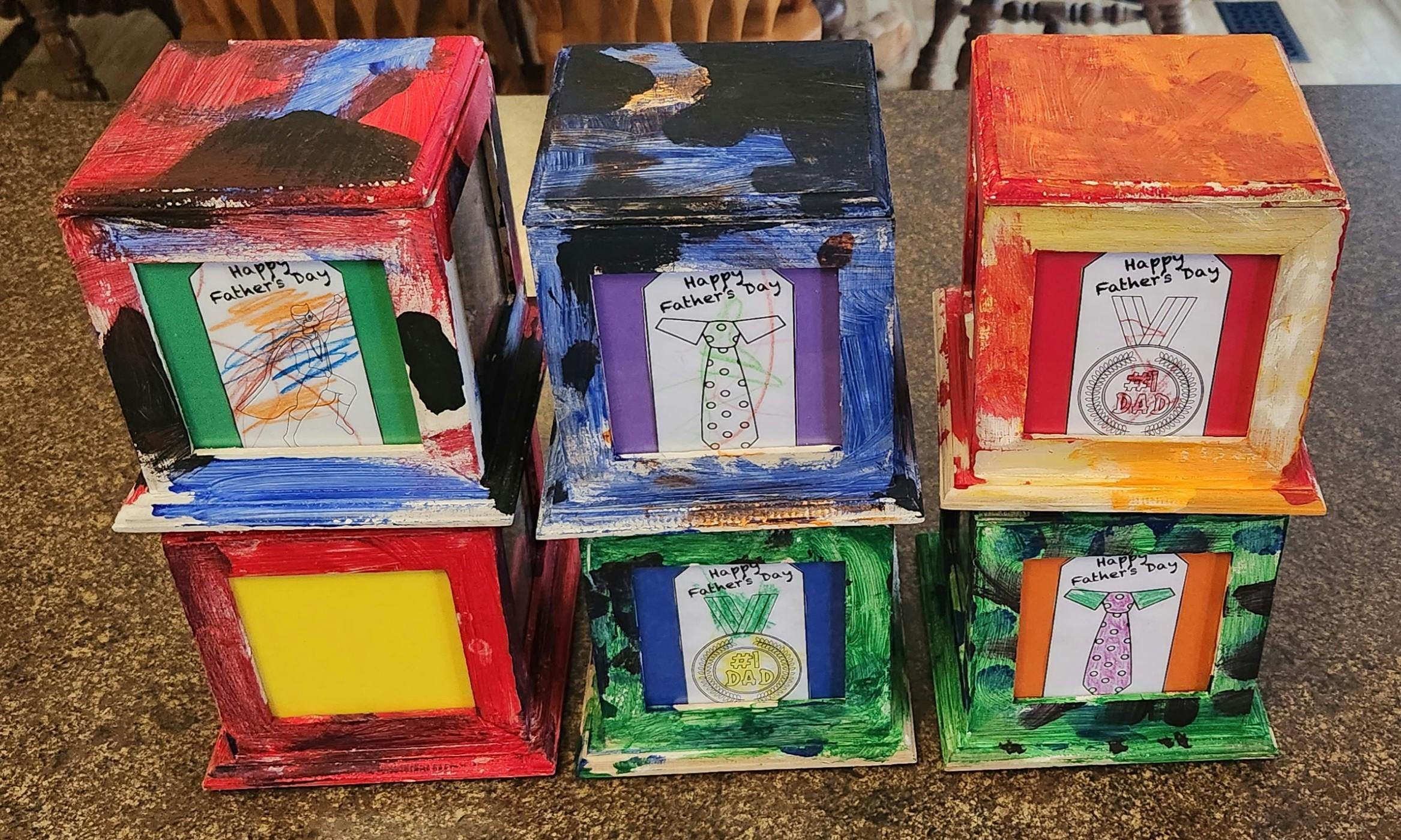 Three stacks of painted boxes with drawings on the front