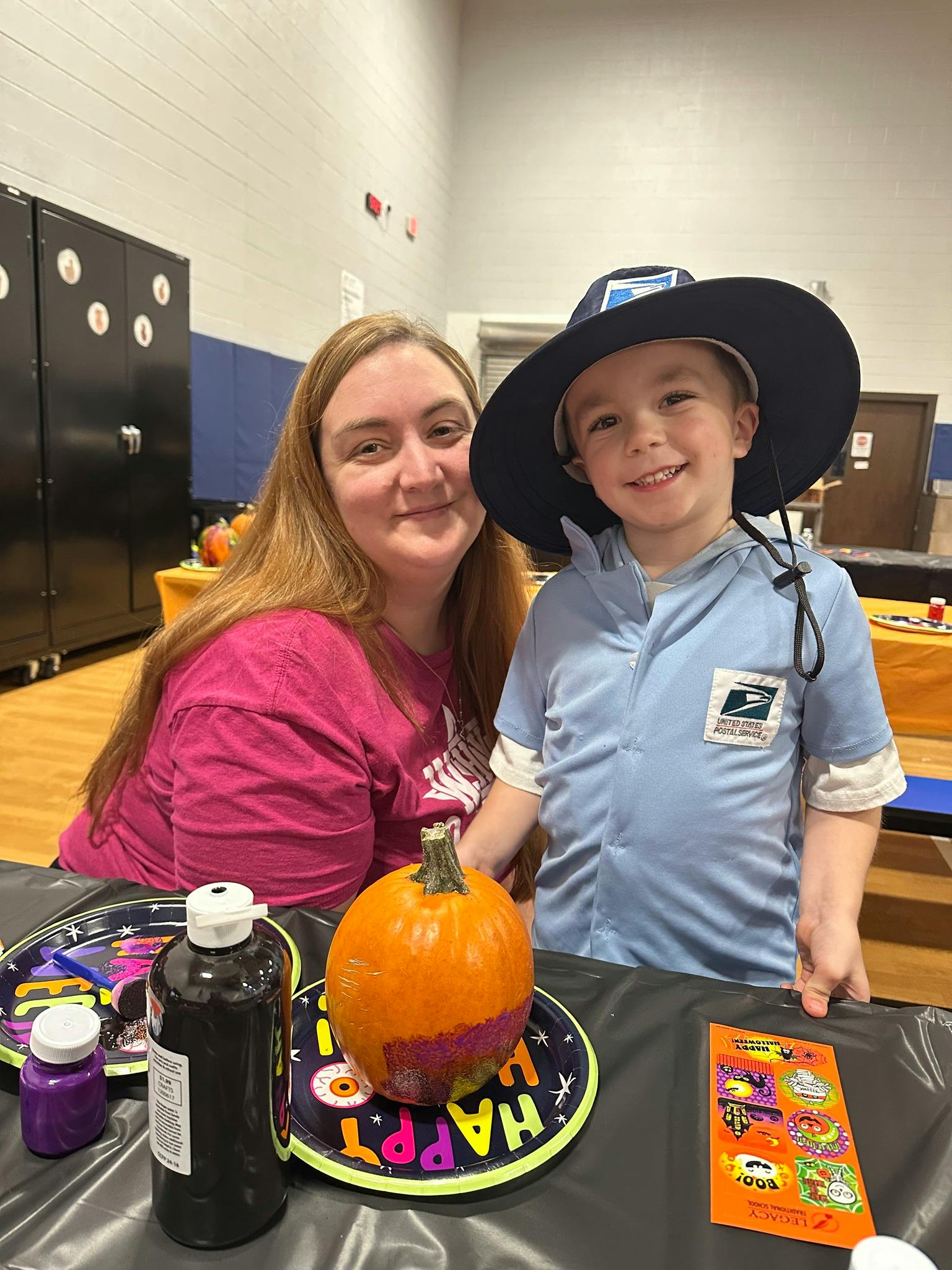 Person and child in costume with a pumpkin on a table