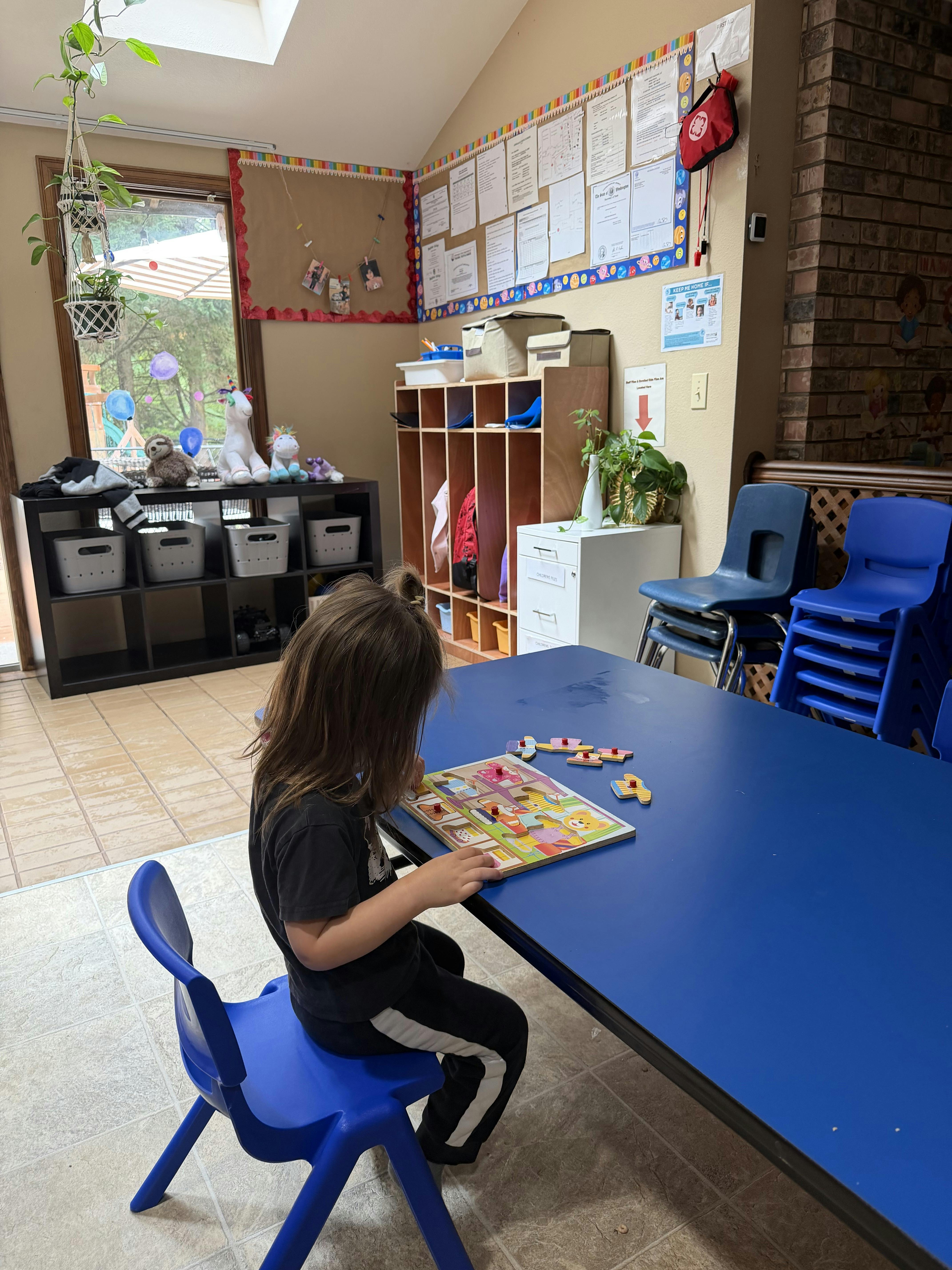 Child sitting at a blue table solving a wooden peg puzzle