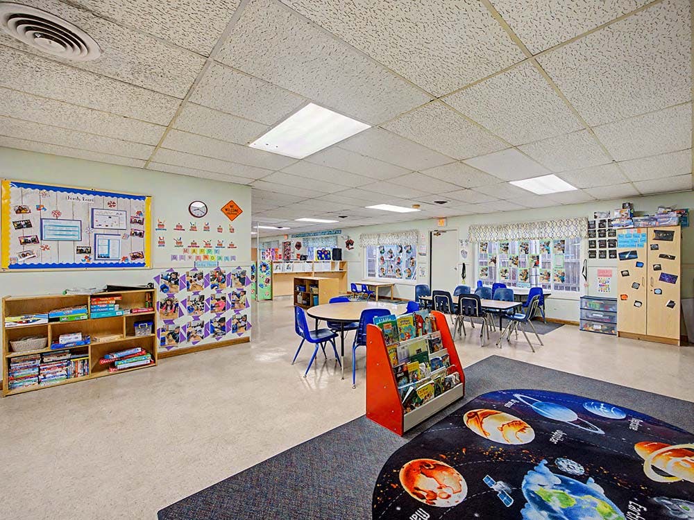 Classroom with small tables and chairs, bookshelves, and bulletin boards