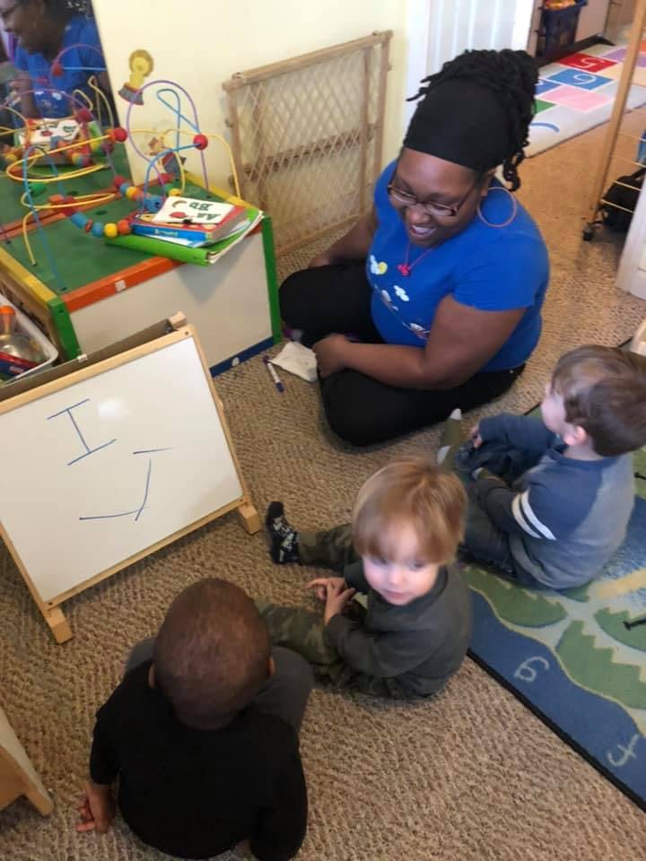 Adult and three children sitting on the floor in a classroom