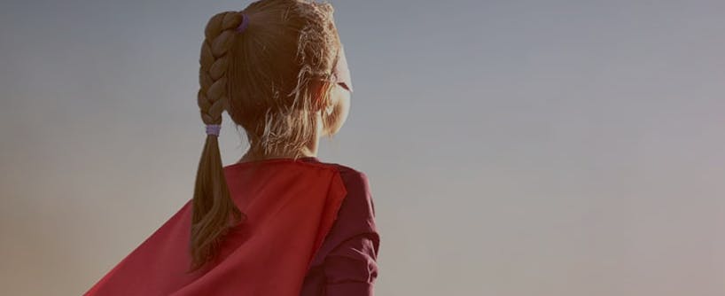 Child with braided hair wearing a red cape, looking away