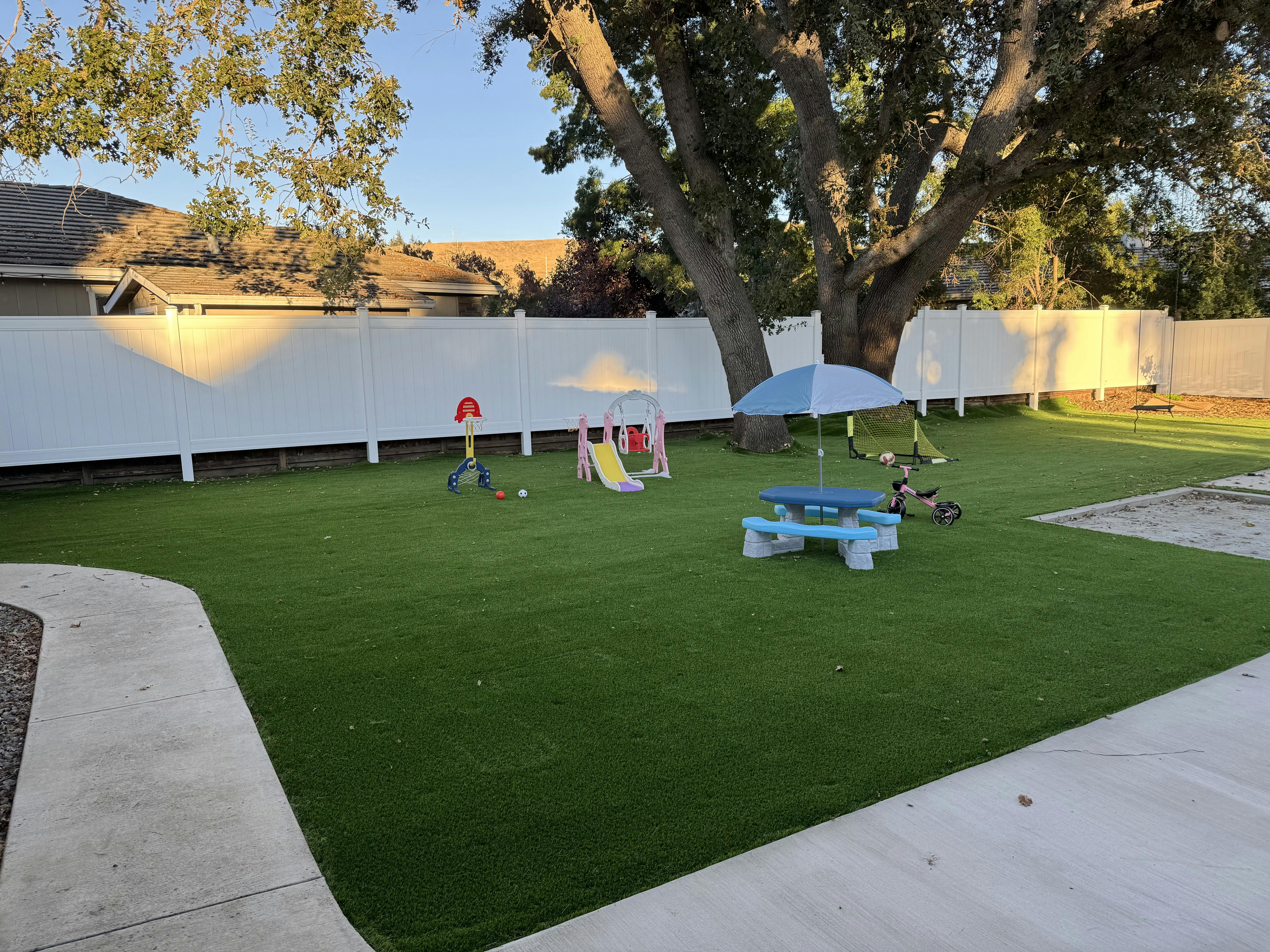 Outdoor play area with artificial turf, a small slide, and a picnic table