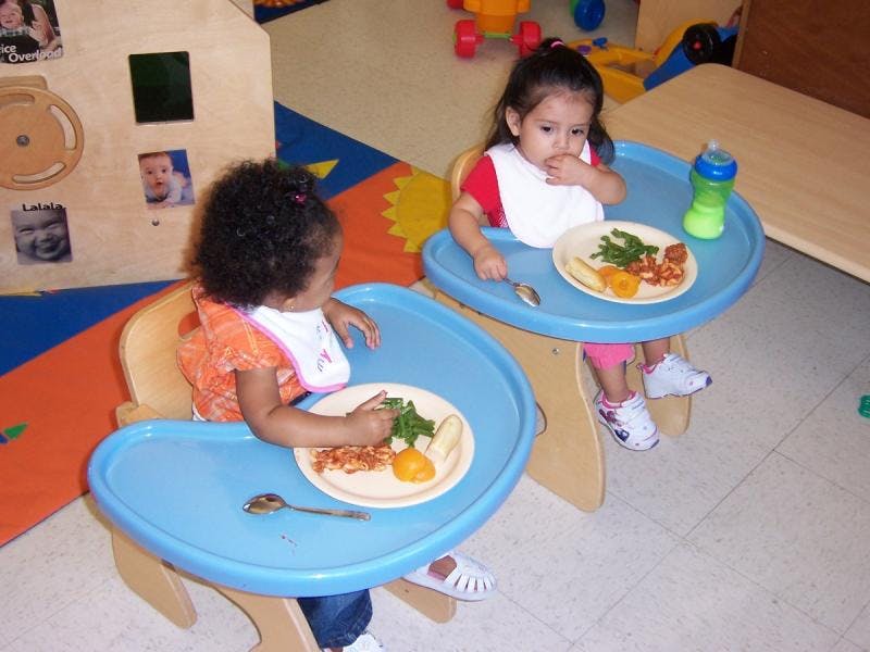 Two children in high chairs eating meals