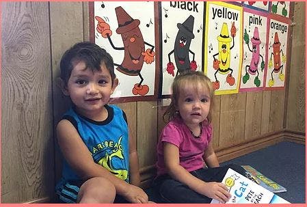 Two children sitting on the floor in front of color charts