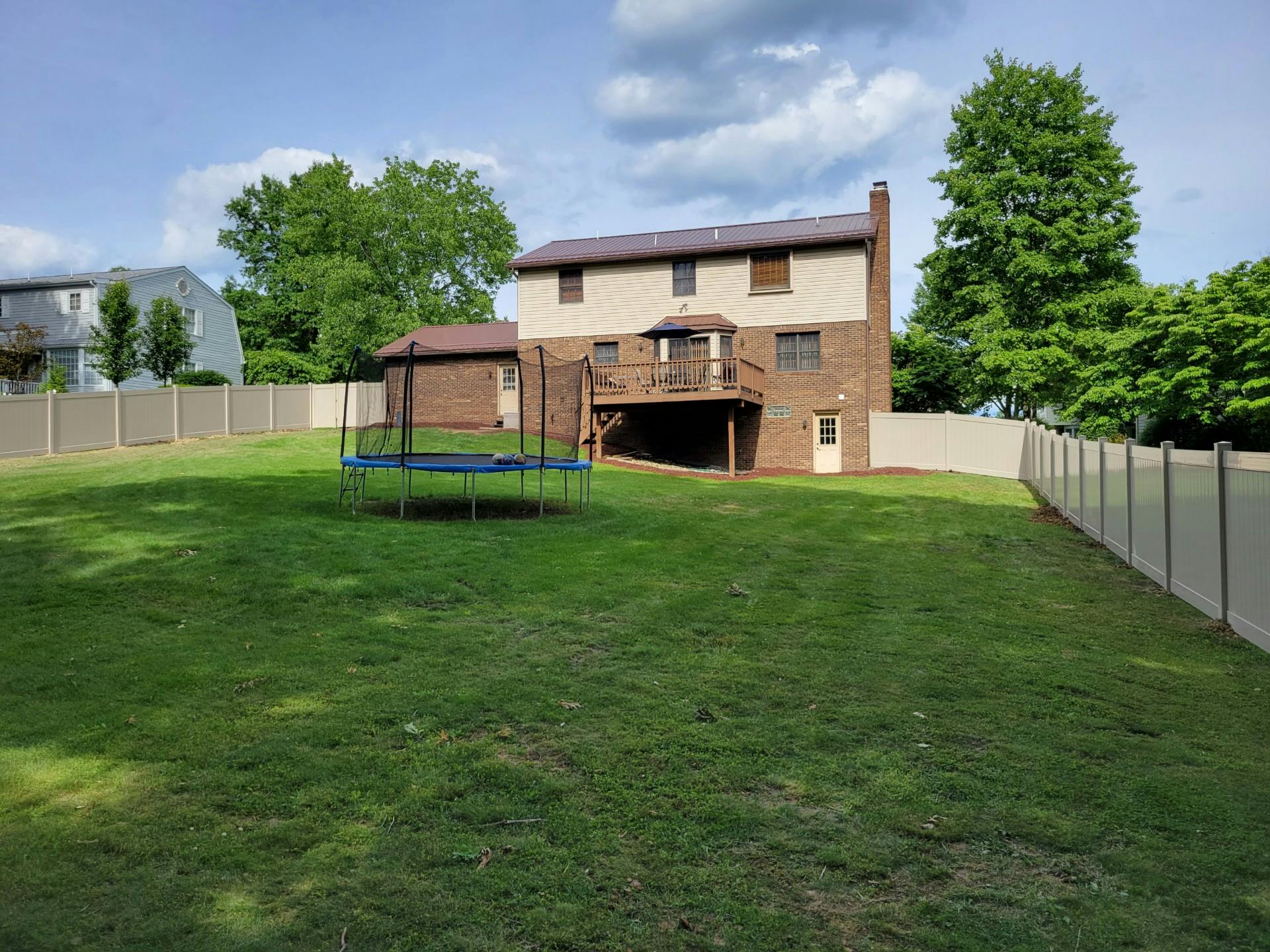 Backyard with a trampoline and a house with a deck